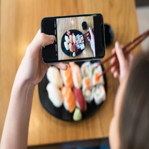 Top view of woman taking photo of sushi on the table